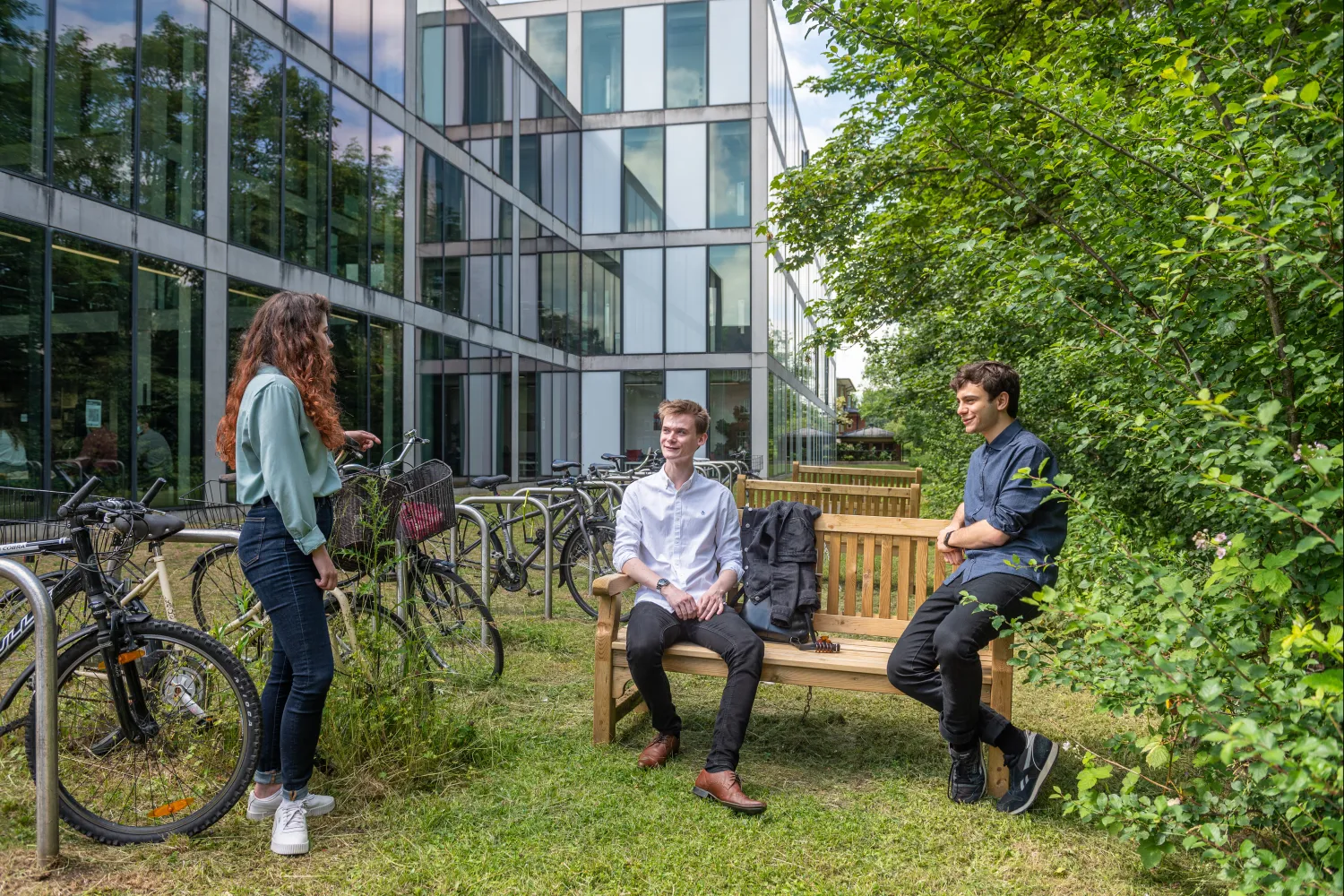 Image of three students outside by a bench
