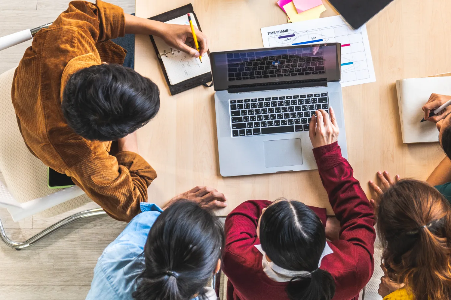 aerial shot of  a group of people huddled around a laptop