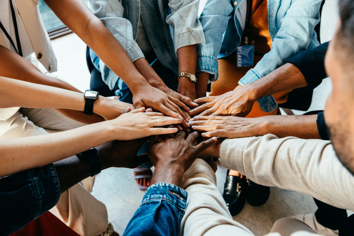 image of a group of people with their hands outstretched into the centre