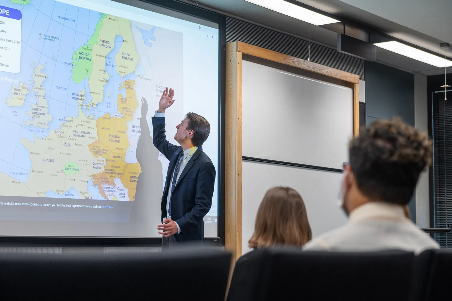Image of a person pointing at a screen in a classroom