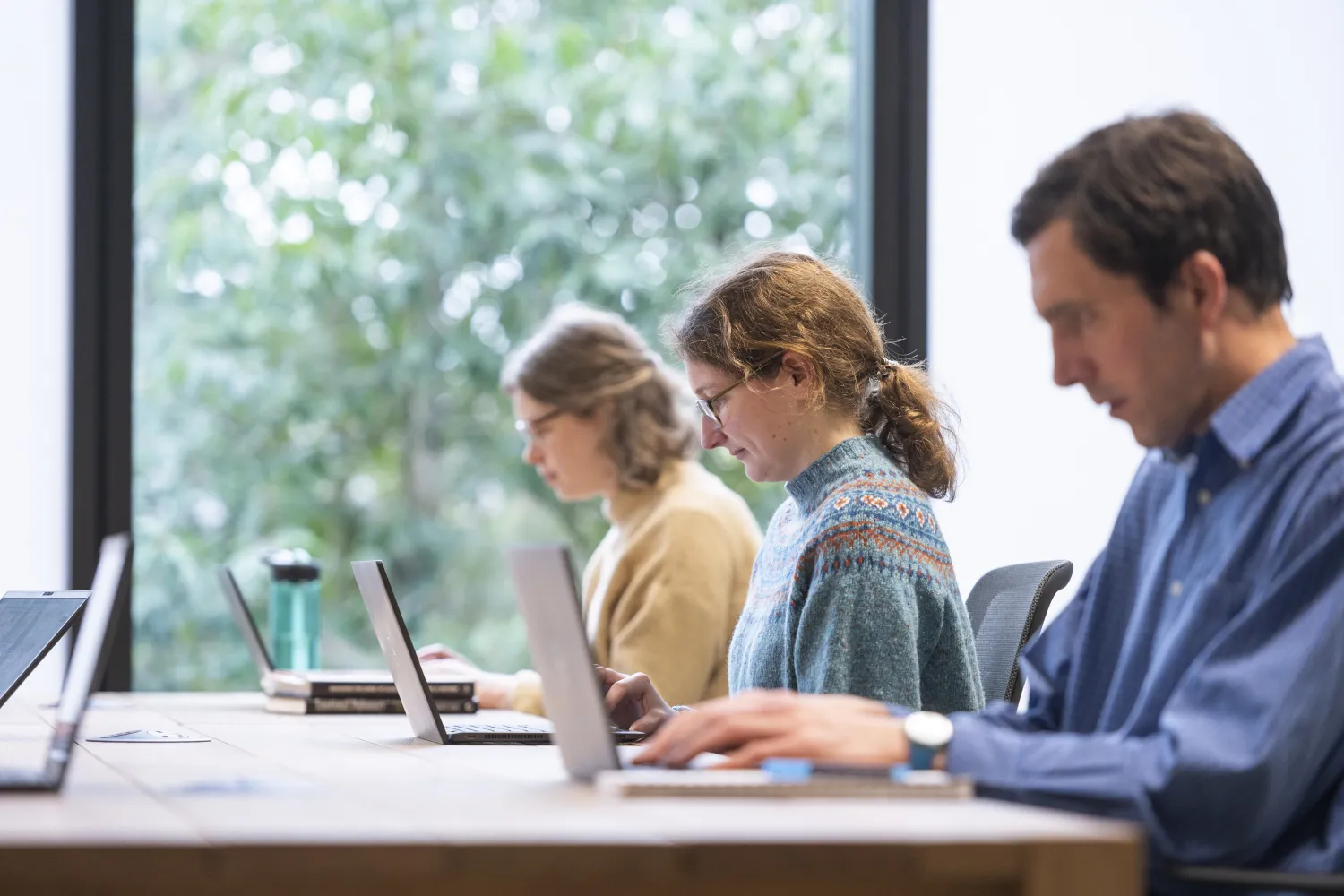 Three people working at laptops in an office