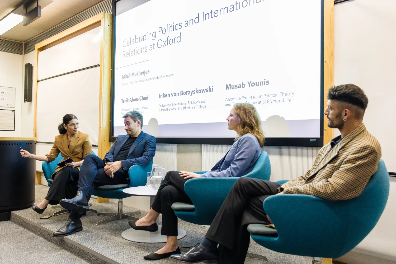 image of a panel of four speakers in front of an projector screen