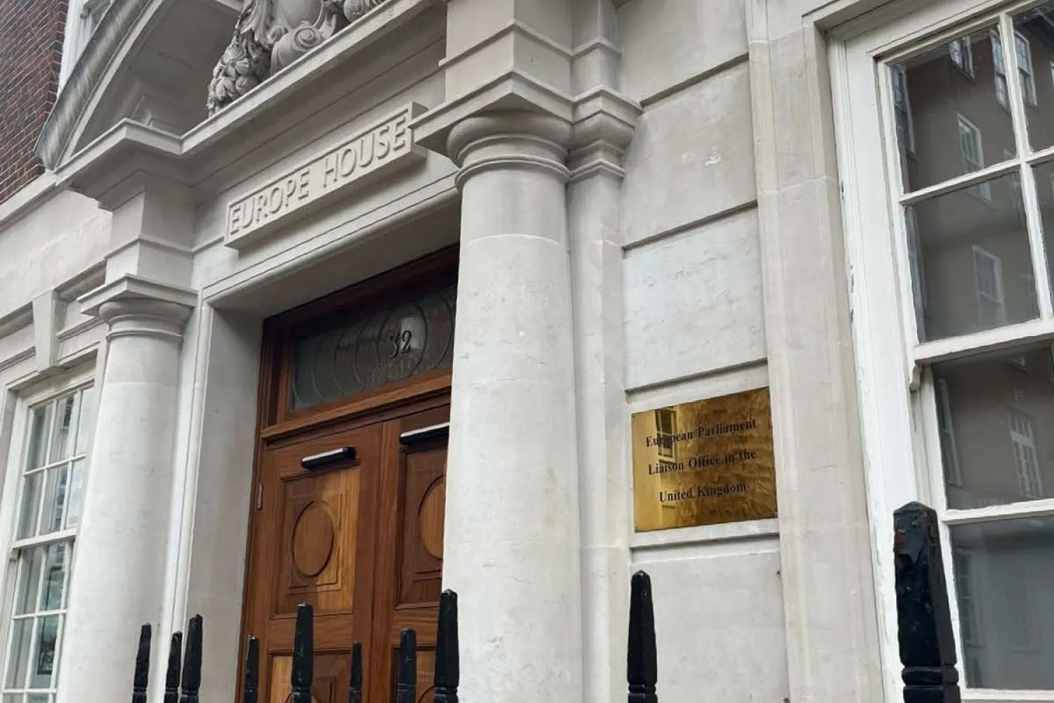 image of a brown door on a property with a white frontage and black railings