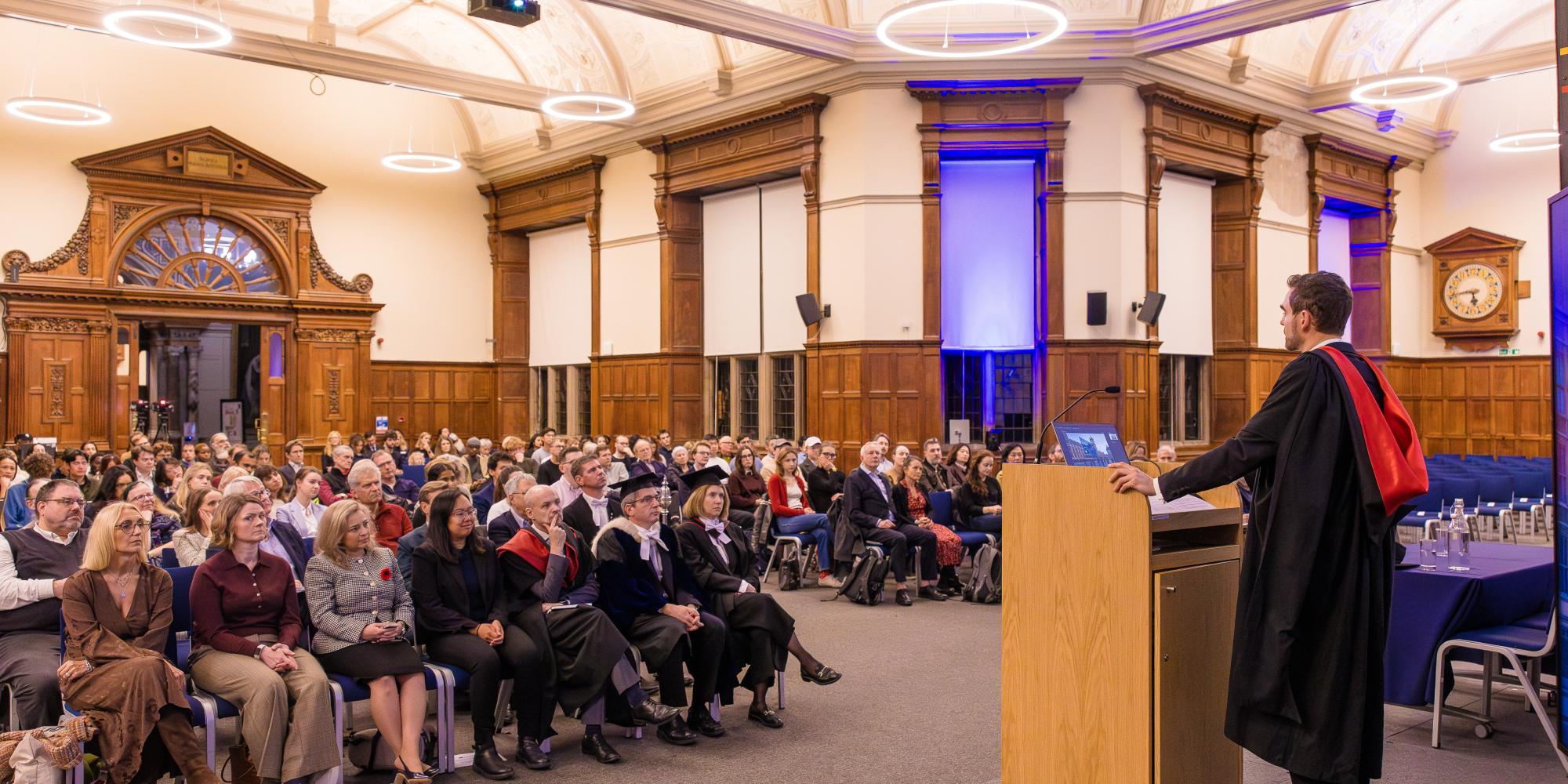 image of a man at a lectern in front of an audience