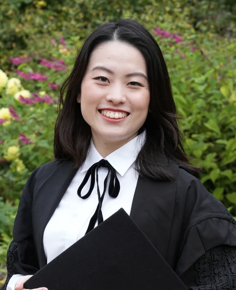 A woman wearing a black gown and white shirt smiling at the camera